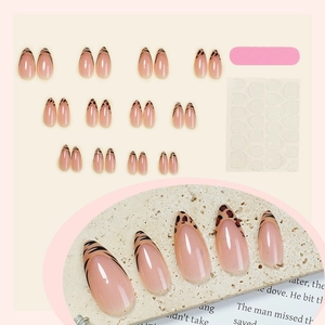 Leopard print French almond press-on nails set with tools on a textured stone background