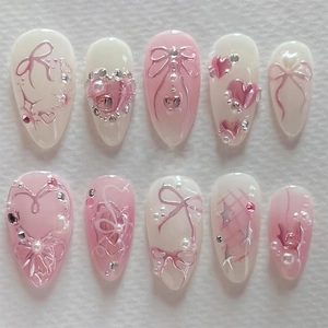 Faux ongles dégradé rose avec nœuds 3D, strass et perles de forme amande