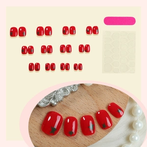 Short red press-on toenails with green star patterns including glue and file kit