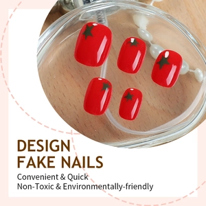Glossy red short press-on nails with green star accents in a stylish still life setting
