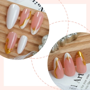 French almond press-on nails in nude pink and white with elegant gold foil accents
