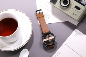 Close-up of hollow dial quartz watch with brown leather strap and vintage props