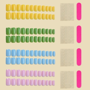 Vue macro de faux ongles courts français en jaune, vert, bleu et rose avec outils