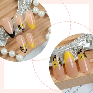 Faux ongles amande avec pointes françaises jaunes et motifs floraux délicats