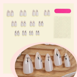 Almond press-on nails with nude base, black floral patterns and glitter line accents
