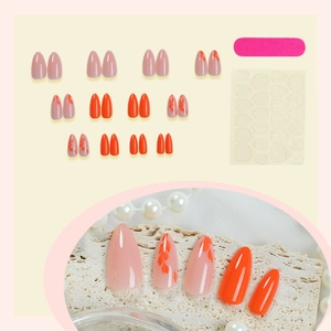 French orange press-on nails with minimalist leaf patterns and nude pink base tones