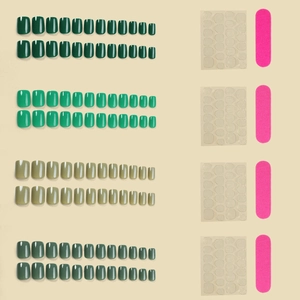 Short press-on nails set in four shades of green with adhesive tabs and nail file