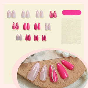 Almond press-on nails set with pink French tips, gold lines, and application tools