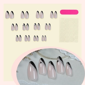 French almond press-on nails with nude pink base, black tips, and silver heart detail