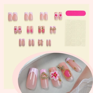 French press-on nails set with 3D pink flowers and gold heart accents on pink base
