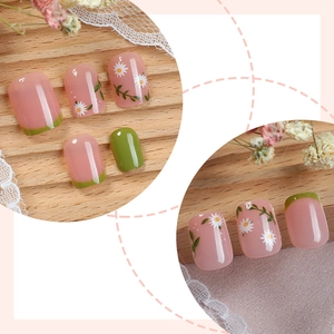 Fresh floral press-on nails with white daisies and green French tips on wood background