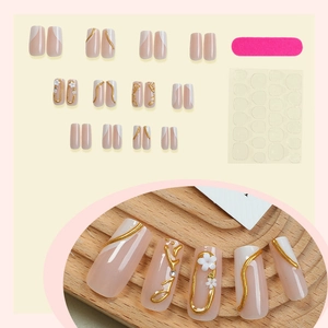 French tip press-on nails set with 3D white flowers and gold edges on wood background