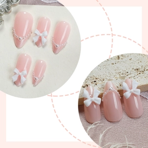 Pink almond press-on nails with white resin bows and delicate pearl heart accents