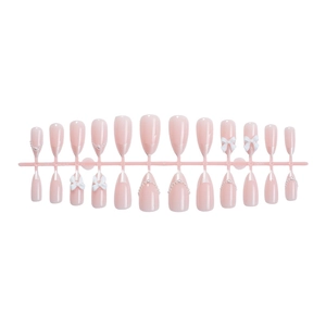 French almond press-on nails in pale pink with white bows and pearl accents