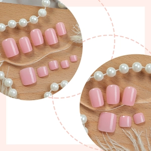 Solid baby pink press-on toenails set with glossy finish on warm wood background
