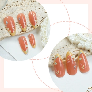 Almond-shaped orange press-on nails with yellow French tips and floral leaf patterns