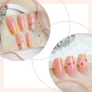 Pink floral press-on nails with strawberry accents and orange French tips in long coffin shape