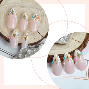 French tip almond press-on nails with pink base, gold stars, and colorful bead accents