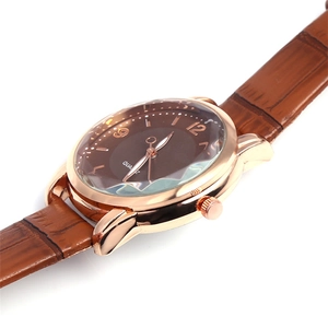Detail of rose gold watch case with geometric cut glass and brown leather strap