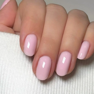 Close-up of glossy soft pink short oval press-on nails on white knit background