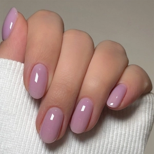 Close-up of glossy lilac oval press-on nails on model's hand with white sweater