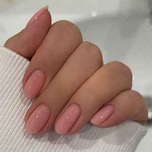 Close-up of glossy soft pink press-on nails in oval shape with natural light