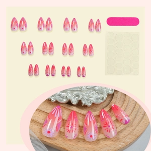 Pink gradient press-on nails set with floral patterns, nail file, and adhesive tabs