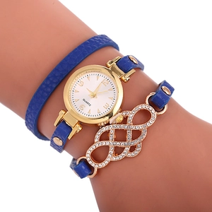 Détail d'une montre bracelet en cuir bleu avec cadran doré et breloque en strass