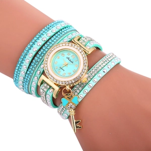 Détail d'une montre bracelet vert menthe avec breloques papillon dorées et strass