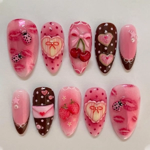 Dettaglio nail art 3D con rilievi fragola e coccinella in rosa e color cioccolato