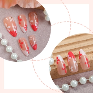 French almond press-on nails with red tips and floral art on a pink background