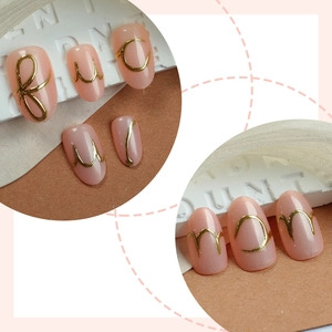 Irregular metal line press-on nails in nude pink with 3D gold letter art accents