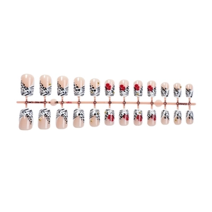 French zebra print press-on nails with red flowers and gold beads on a pink display rack