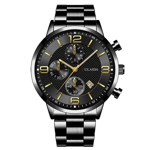 Detail of black textured chronograph watch with golden numerals and stainless steel band
