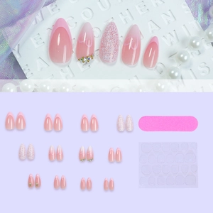 Pink gradient press-on nail kit with glitter accents, heart designs and manicure tools