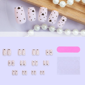 Handmade pink matte press-on nails with black polka dots and hearts, including full tool kit