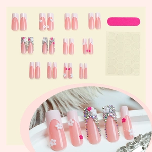 French tip press-on nails in pink and white with 3D floral accents and rhinestones