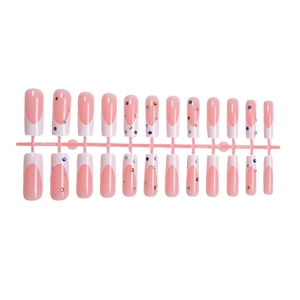 Pink French press-on nails with white tips and colorful rhinestones on a plastic rack