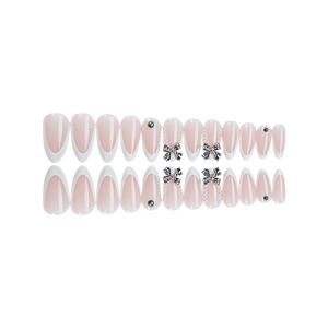 French tip press-on nails in nude pink with silver bows and pearl accents