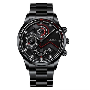 Detail view of the black steel watch dial with red V-shaped lines and date window