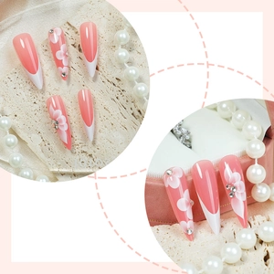 Faux ongles French rose et blanc avec art floral et strass en forme de stylet long et élégant