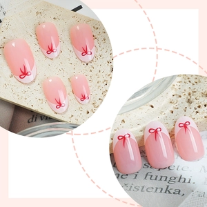 Short oval press-on nails with pink base, white French tips, and red bow designs