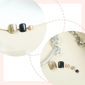 Detail view of luxurious black and liquid gold press-on toenails with glitter finish