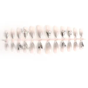 Macro view of ombre almond press-on nails with 3D silver butterfly and rhinestone details