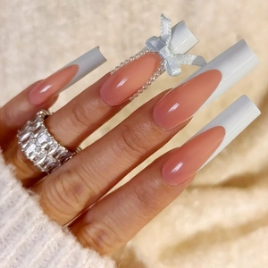 Detail of long square French nails with elegant pearls and a 3D blue ribbon bow