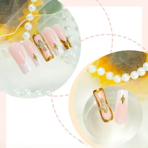 Detail of long French nails with golden 3D crosses and star accents over pink ombre