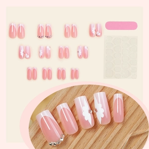 Faux ongles French rose avec motifs floraux blancs et petits strass brillants inclus