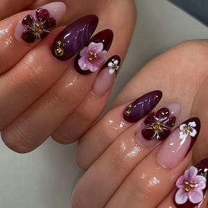 French almond fake nails featuring 3D floral carvings and golden beads in purple and pink