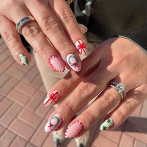 Detailed view of almond-shaped Christmas press-on nails with holly and bow festive designs