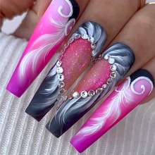 Gros plan de faux ongles ballerine longs avec plume rose et cœurs en strass brillants